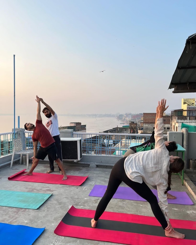Hatha Yoga Teacher Ayush correcting to student in Trikonasana (Triangle Pose) Position.