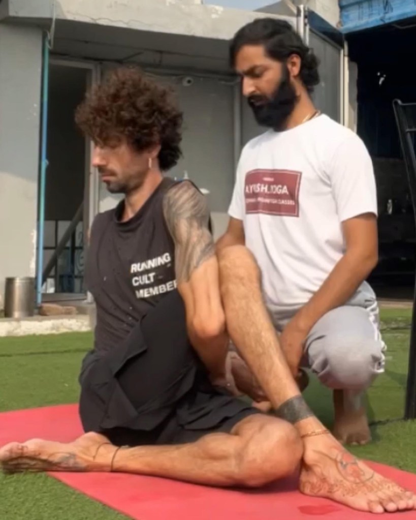 Hathayoga Teacher Ayush helping his student in Ardha Matsyendrasana (Half Lord of the Fishes Pose) known as also Spinal Twist. 
