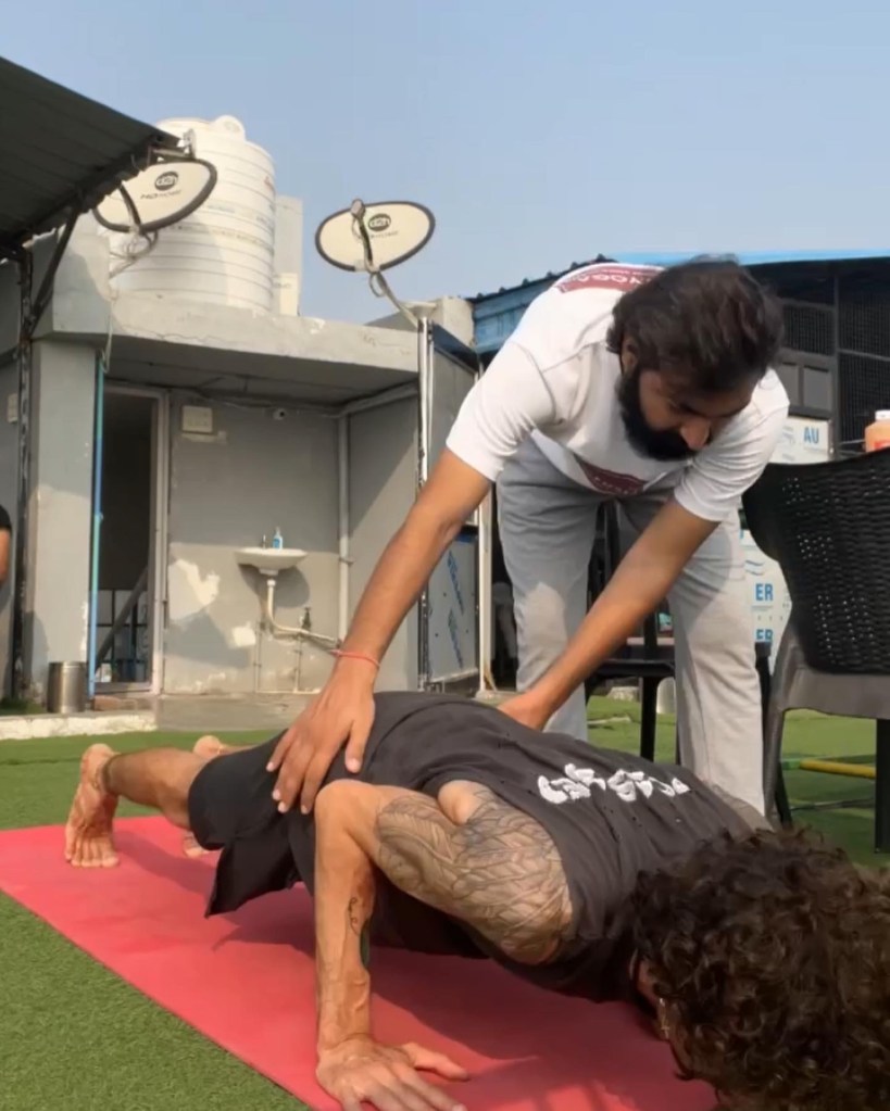 Hathayoga Teacher Ayush helping his student in Chaturanga Dandasana or Four-Limbed Staff pose, also known as Low Plank. 