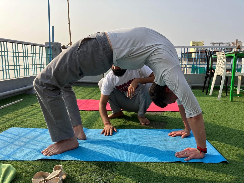 Hathayoga Teacher Ayush helping his student in Chakrasana (Wheel Pose). 