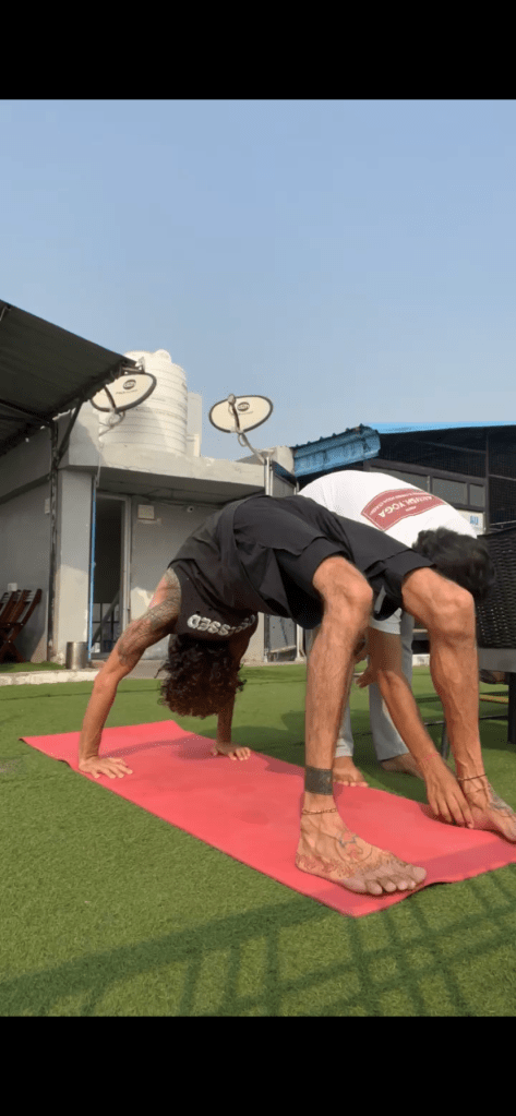Hathayoga Teacher Ayush correcting his student in Chakrasana or Urdhva Dhanurasana is a backbending pose also known as a Wheel Pose. 