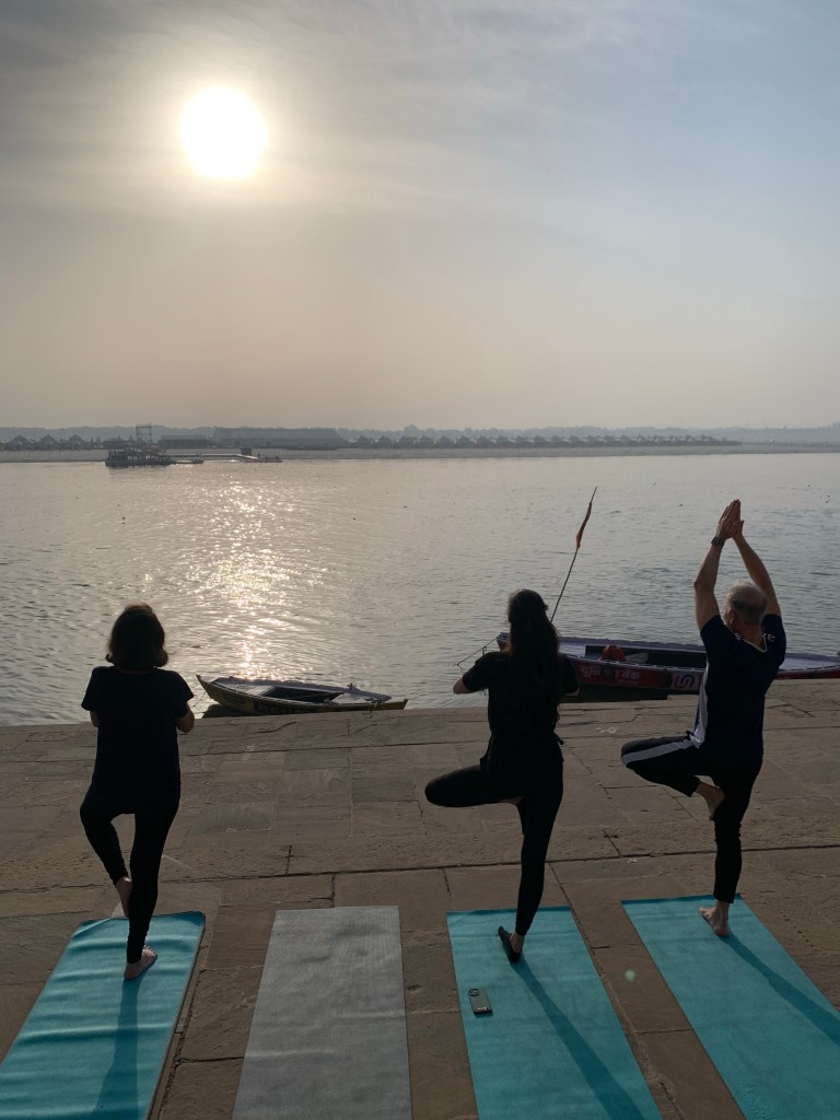 Yoga teacher Ayush students performing Tree Pose in Varanasi over looking Ganga. 