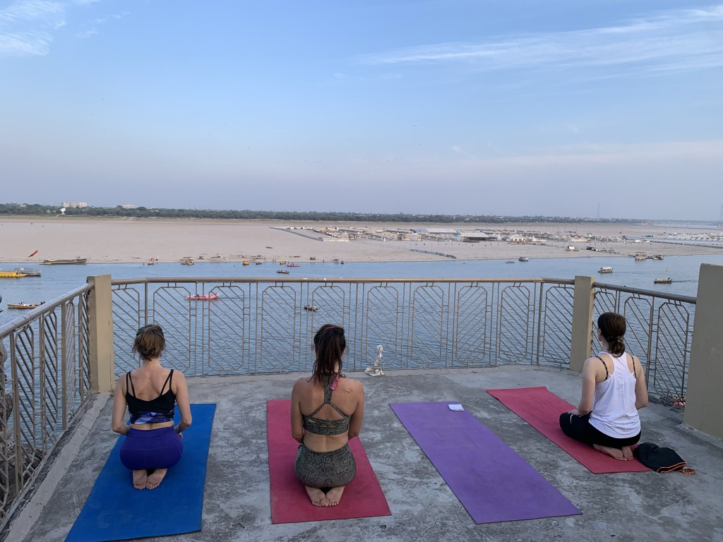 Yoga teacher Ayush students performing Vajrasana overlooking Ganges in Varanasi. 
